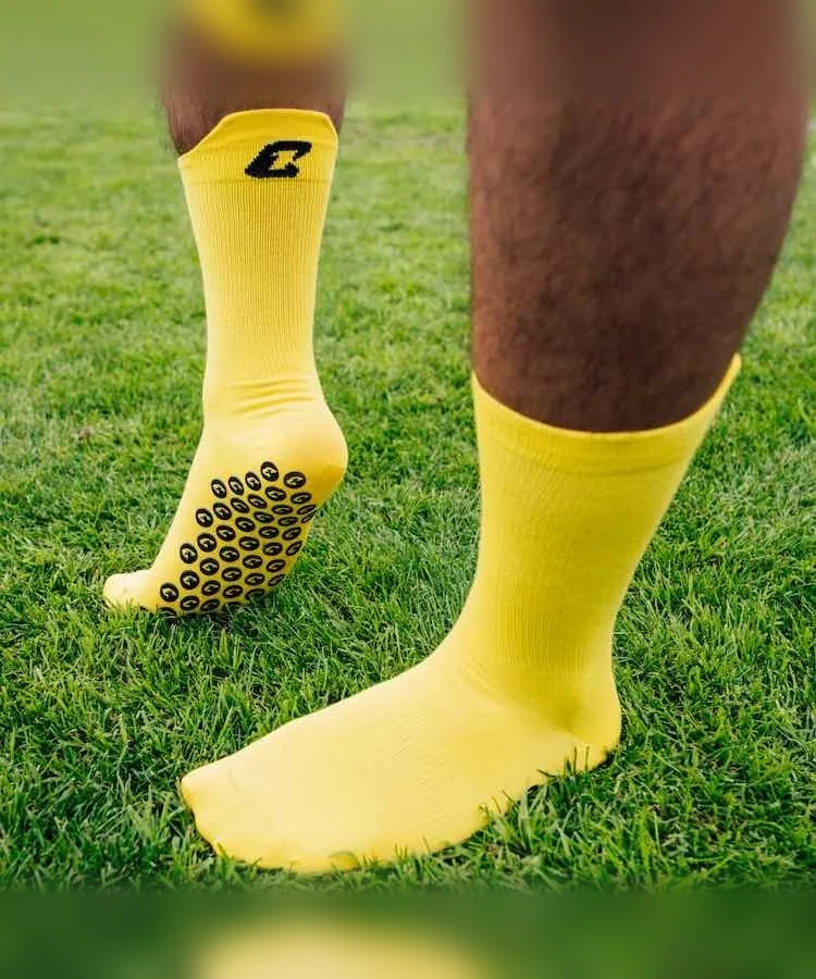 Performance Grip Socke in Gelb getragen auf dem Rasen – Grip-Elemente an der Sohle sichtbar