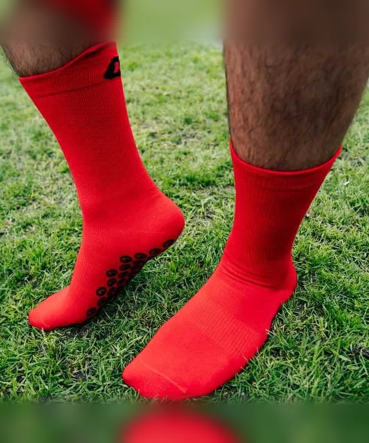 Performance Grip Socke in Rot getragen auf dem Rasen – Grip-Elemente an der Sohle sichtbar