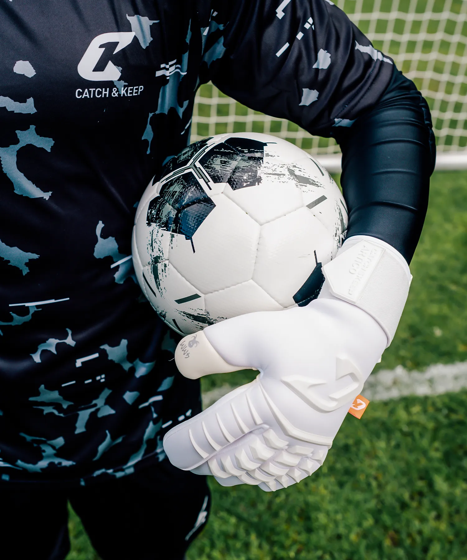 Torwart hält den Ball unter dem Arm, weißer Artico Torwarthandschuh mit 4MM-Octopus-Logo im Detail