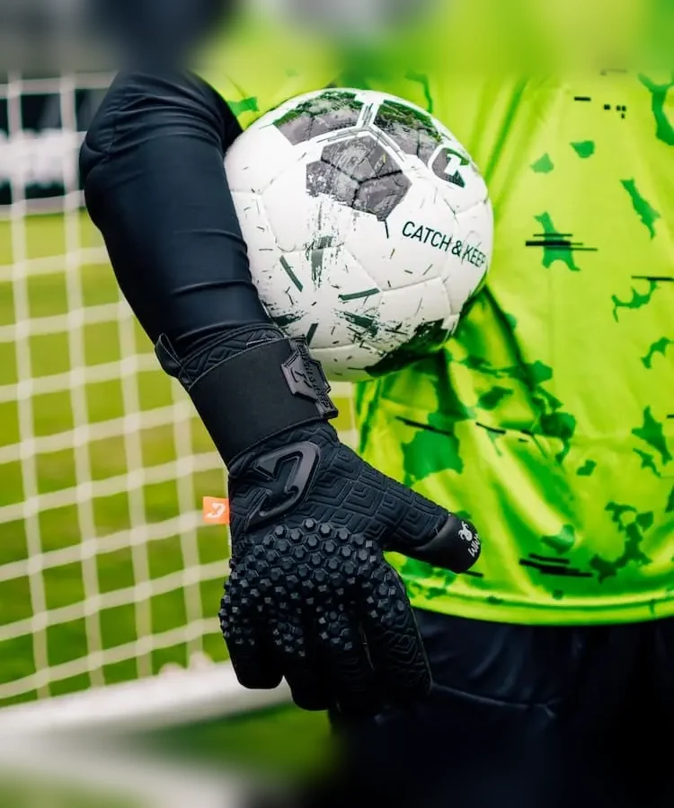 Schwarzer Nero Torwarthandschuh hält einen Ball vor einem grünen Torwarttrikot
